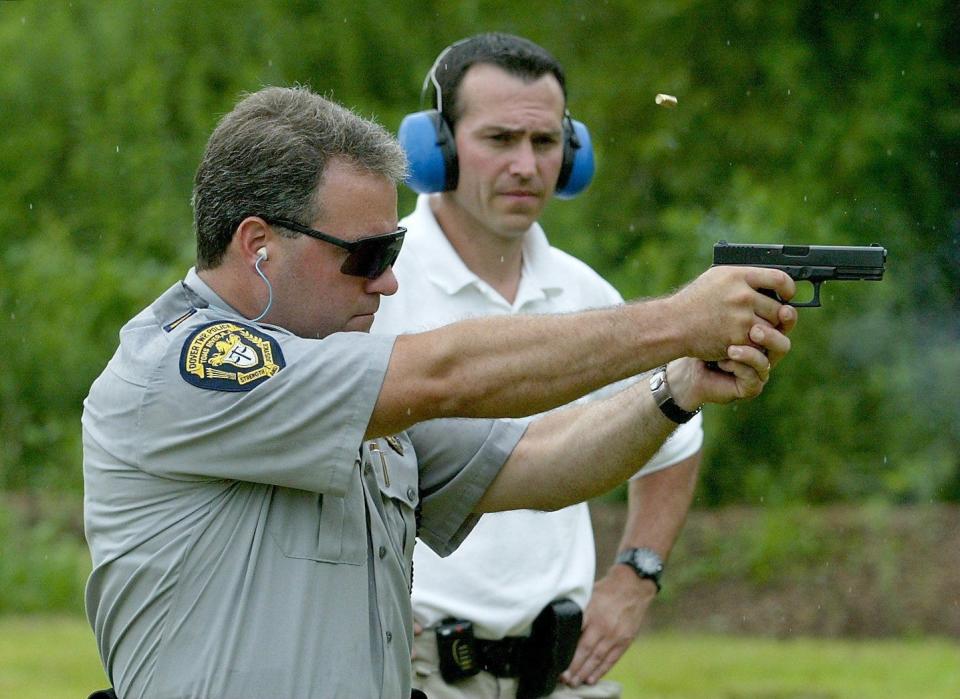 Dover (N.J.) Township Police Sgt. Richie Ross observes Lt. Mitch Little (foreground) as he fires the newly-issued Glock .40 caliber semi-automatic pistol at the local police range on August 7, 2003.