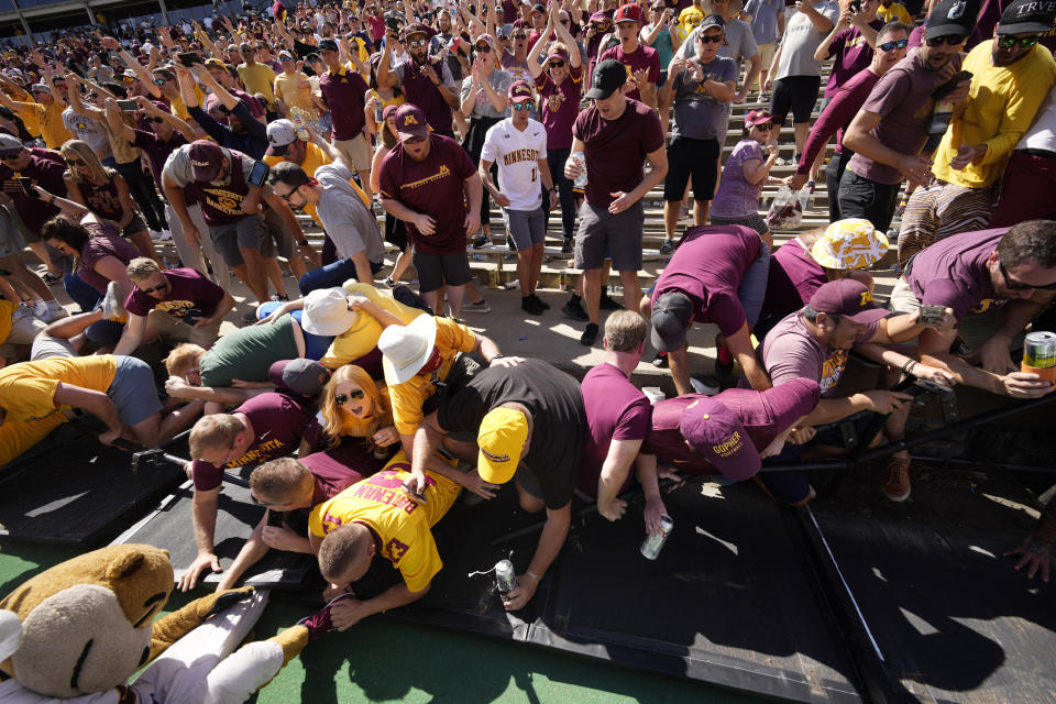 Minnesota fans collapse the fence around the field while congratulating players after the second half of an NCAA college football game against Colorado Saturday, Sept. 18, 2021, in Boulder, Colo. Minnesota won 30-0. (AP Photo/David Zalubowski)