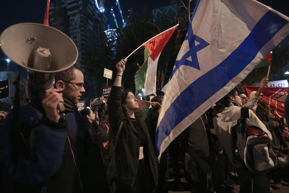 Protesters wave Israeli and Palestinian flags during a rally against plans by Prime Minister Benjamin Netanyahu's new government to overhaul the judicial system, in Tel Aviv, Israel, Saturday, Feb. 18, 2023. (AP Photo/Tsafrir Abayov)