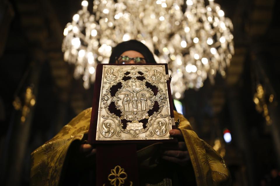 An Orthodox priest holds a copy of a Bible at the Patriarchal Church of St. George prior to a meeting of Ecumenical Patriarch Bartholomew I, Ukrainian President Petro Poroshenko, and Metropolitan Epiphanius, the head of the independent Ukrainian Orthodox Church, in Istanbul, Turkey, Saturday, Jan. 5, 2019. (AP Photo/Emrah Gurel)