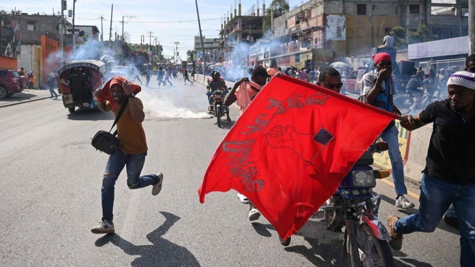 Personas corren en la capital de Haití, Puerto Príncipe, en medio de un acto de violencia