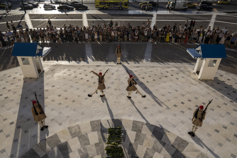 Tourists watch the changing of the Presidential guards ceremony at the tomb of the unknown soldier , in central Athens , on Friday, Sept. 30, 2022. Greece is on course to beat its annual record for tourism revenue as southern European Union members made a surprise recovery following a two-year travel slump caused by the pandemic. (AP Photo/Petros Giannakouris)