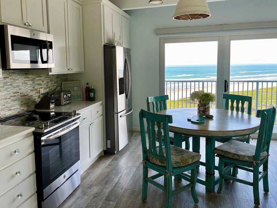 The inside of a kitchen overlooking a beach.