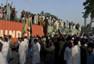 Protesters try to climb on a shipping container at a rally against French President Emmanuel Macron and republishing of caricatures of the Prophet Muhammad they deem blasphemous, in Islamabad, Pakistan, Friday, Oct. 30, 2020. Muslims have been calling for both protests and a boycott of French goods in response to France's stance on caricatures of Islam's most revered prophet. (AP Photo/A.H. Chaudary)