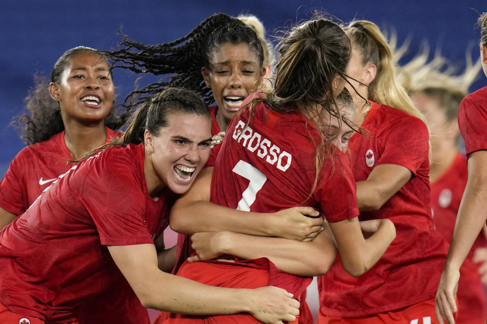 FILE - Teammates embrace Canada's Julia Grosso after she scored the winning goal against Sweden in the women's soccer match for the gold medal at the 2020 Summer Olympics, Friday, Aug. 6, 2021, in Yokohama, Japan. (AP Photo/Fernando Vergara, File)