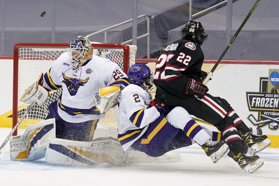 The puck flies past Minnesota State goaltender Dryden McKay (29) as Akito Hirose (2) clears St. Cloud State's Joe Molenaar (22) from the crease during the second period of an NCAA men's Frozen Four hockey semifinal in Pittsburgh, Thursday, April 8, 2021. (AP Photo/Keith Srakocic)