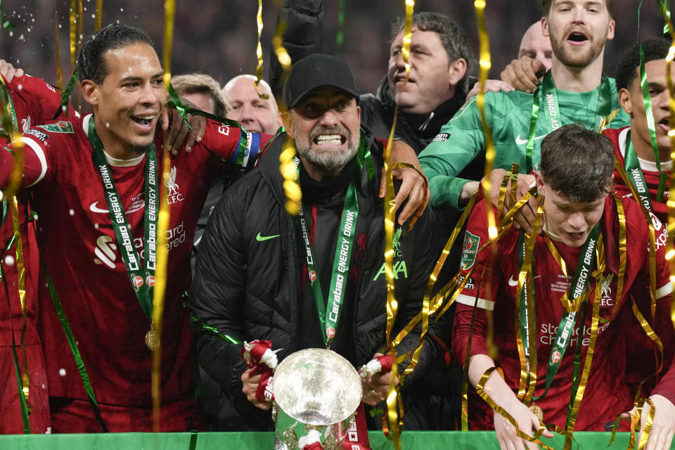 Liverpool's manager Jurgen Klopp lifts the trophy next to Liverpool's Virgil van Dijk as the team celebrates winning the English League Cup final soccer match between Chelsea and Liverpool at Wembley Stadium in London, Sunday, Feb. 25, 2024. (AP Photo/Alastair Grant)