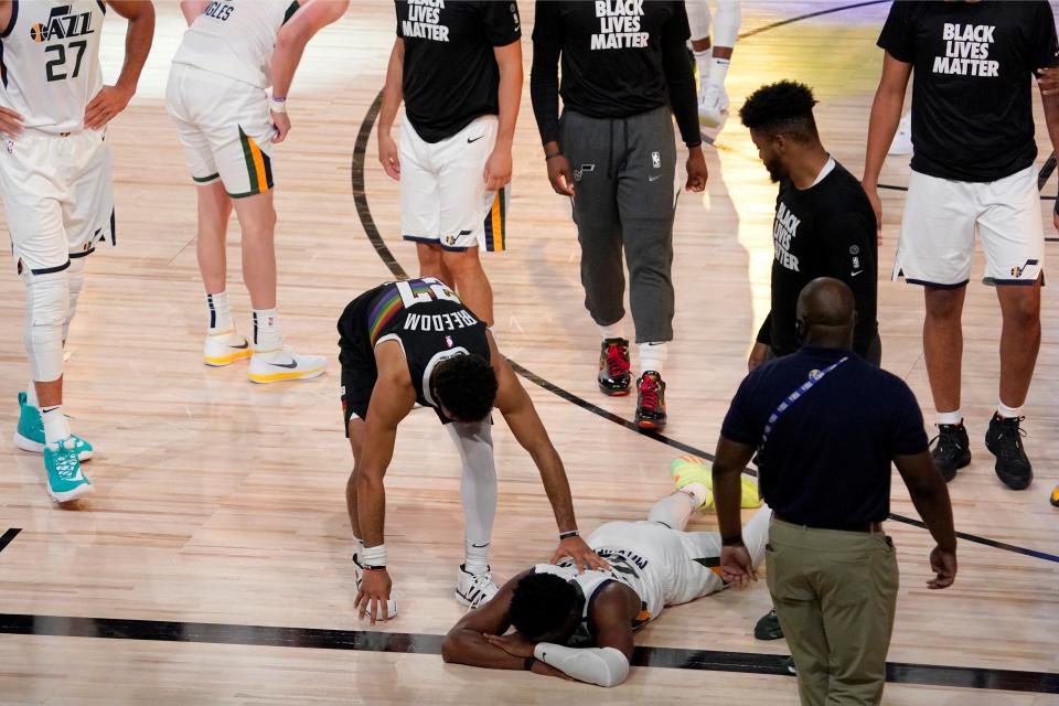 Denver Nuggets' Jamal Murray, center left, reaches down to console Utah Jazz's Donovan Mitchell (45), on floor, after the Nuggets 80-78 win during an NBA first round playoff basketball game, Tuesday, Sept. 1,2020, in Lake Buena Vista, Fla. (AP Photo/Mark J. Terrill) ORG XMIT: TXTG188