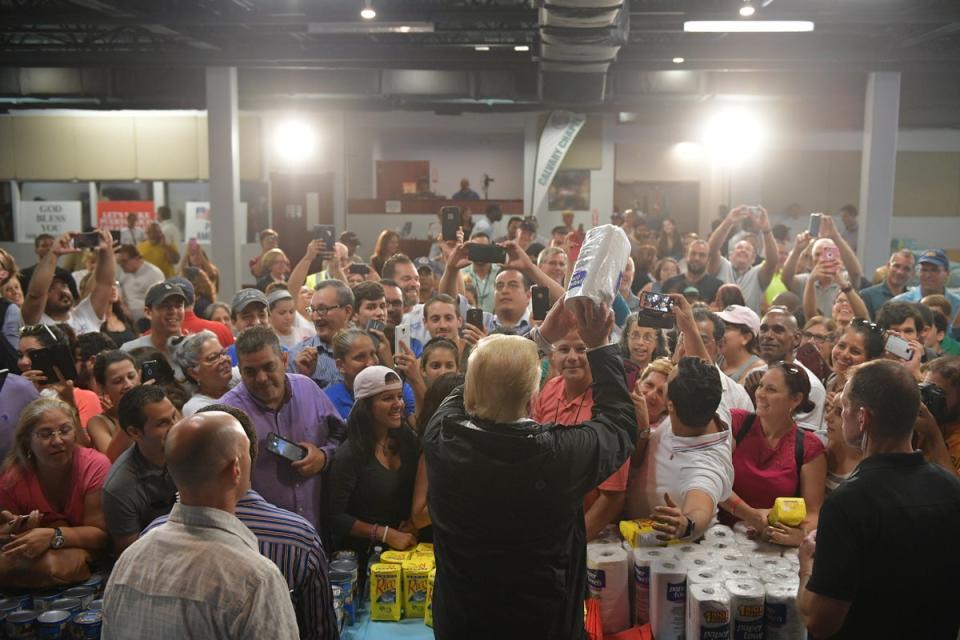 US President Donald Trump throws a paper towel roll as he visits the Cavalry Chapel in Guaynabo, Puerto Rico on October 3, 2017 (AFP via Getty Images)