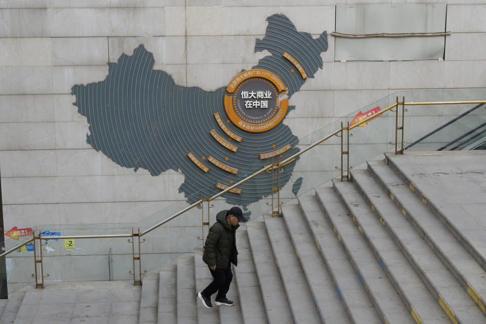A man walks past a depiction of Evergrande properties across a China map at a partially shuttered Evergrande commercial complex in Beijing, Monday, Jan. 29, 2024. Chinese property developer China Evergrande Group on Monday was ordered to liquidate by a Hong Kong court, after the firm was unable to reach a restructuring deal with creditors. (AP Photo/Ng Han Guan)