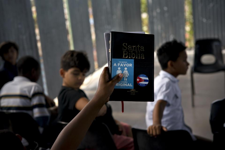 A child holds up a bible with a sticker that reads "I am in favor of the original design " during bible school at an evangelical church in Havana, Cuba, Sunday, Jan. 27, 2019. Among evangelical denominations with public figures on their members, the Pentecostals, Methodists and Baptists alone say they have more than 260,000 followers.(AP Photo/Ramon Espinosa)
