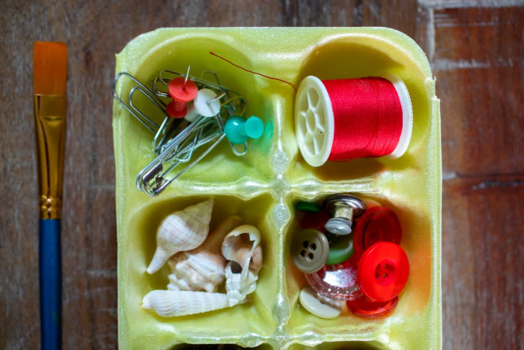 A styrofoam tray is used to organize crafts such as needle and thread.