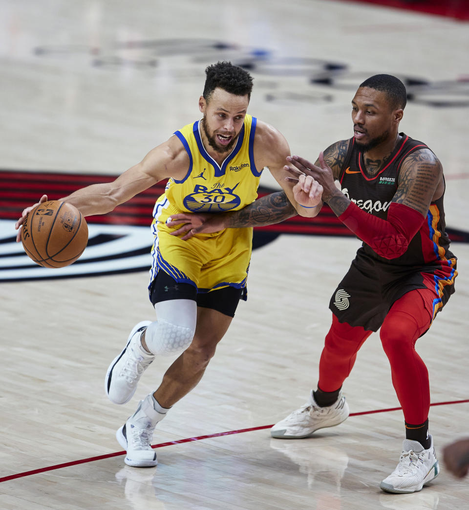 Golden State Warriors guard Stephen Curry, left, dribbles past Portland Trail Blazers guard Damian Lillard during the first half of an NBA basketball game in Portland, Ore., Wednesday, March 3, 2021. (AP Photo/Craig Mitchelldyer)