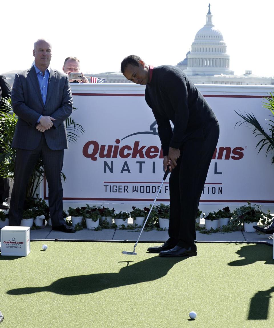 Tiger Woods, center, putts during a putting challenge at the Newseum in Washington, Monday, March 24, 2014. Woods and Quicken Loans Chief Executive Officer Bill Emerson, left, participated in the putting challenge to have the mortgage payments paid for three military families for one month. Earlier, Woods and Emerson announced that Quicken Loans had signed a multi-year agreement to become the title sponsor of the Quicken Loans National to be played at Congressional in Bethesda, Md., in June. (AP Photo/Susan Walsh)