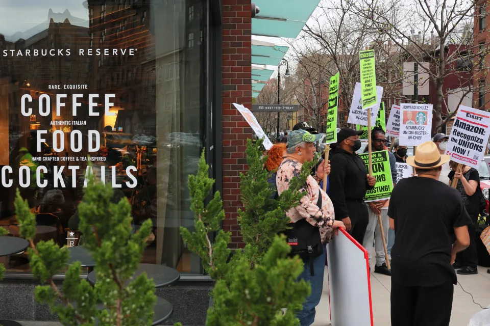 NEW YORK, NEW YORK - APRIL 14: People hold signs while protesting in front of Starbucks on April 14, 2022 in New York City. Activists gathered to protest Starbucks&#39; CEO Howard Schultz anti-unionization efforts and demand the reinstatement of workers fired for trying to unionize. (Photo by Michael M. Santiago/Getty Images)