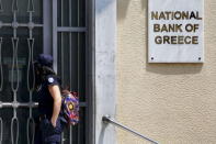 A coast guard officer looks through a locked gate at a National Bank of Greece branch in Piraeus port near Athens, Greece June 30, 2015. REUTERS/Yannis Behrakis