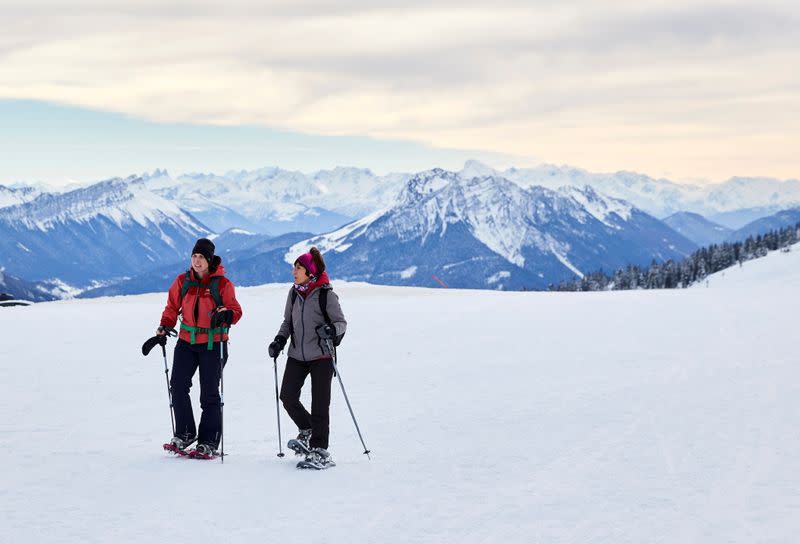 People walk with snowshoes on a winter day in Semnoz near Annecy