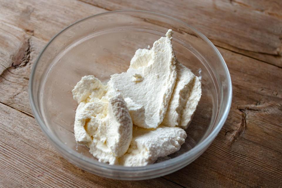 homemade ricotta cheese in a glass bowl on old wooden table background closeup side view selective soft focus text copy space healthy eating brekfast concept