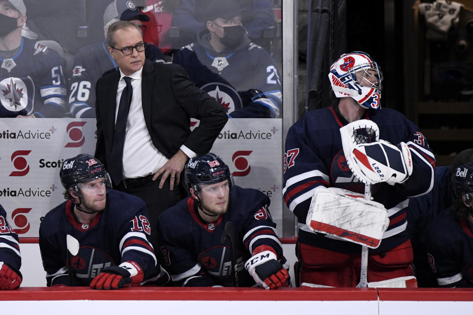 Winnipeg Jets head coach Paul Maurice, Jansen Harkins (12), Kristian Vesalainen (93) and goaltender Connor Hellebuyck (37) watch from the bench against the Buffalo Sabres during the third period of an NHL hockey game, Tuesday, Dec. 14, 2021 in Winnipeg, Manitoba. (Fred Greenslade/The Canadian Press via AP)
