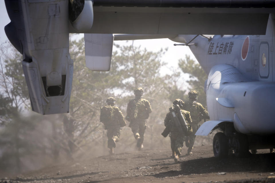 Members of the Japan Ground Self-Defense Force (JGSDF) rush out from a V-22 osprey as they take part in a joint military helicopter borne operation drill between Japan Ground Self-Defense Force (JGSDF) and U.S. Marines at the Higashi Fuji range in Gotemba, southwest of Tokyo, Tuesday, March 15, 2022. (AP Photo/Eugene Hoshiko)