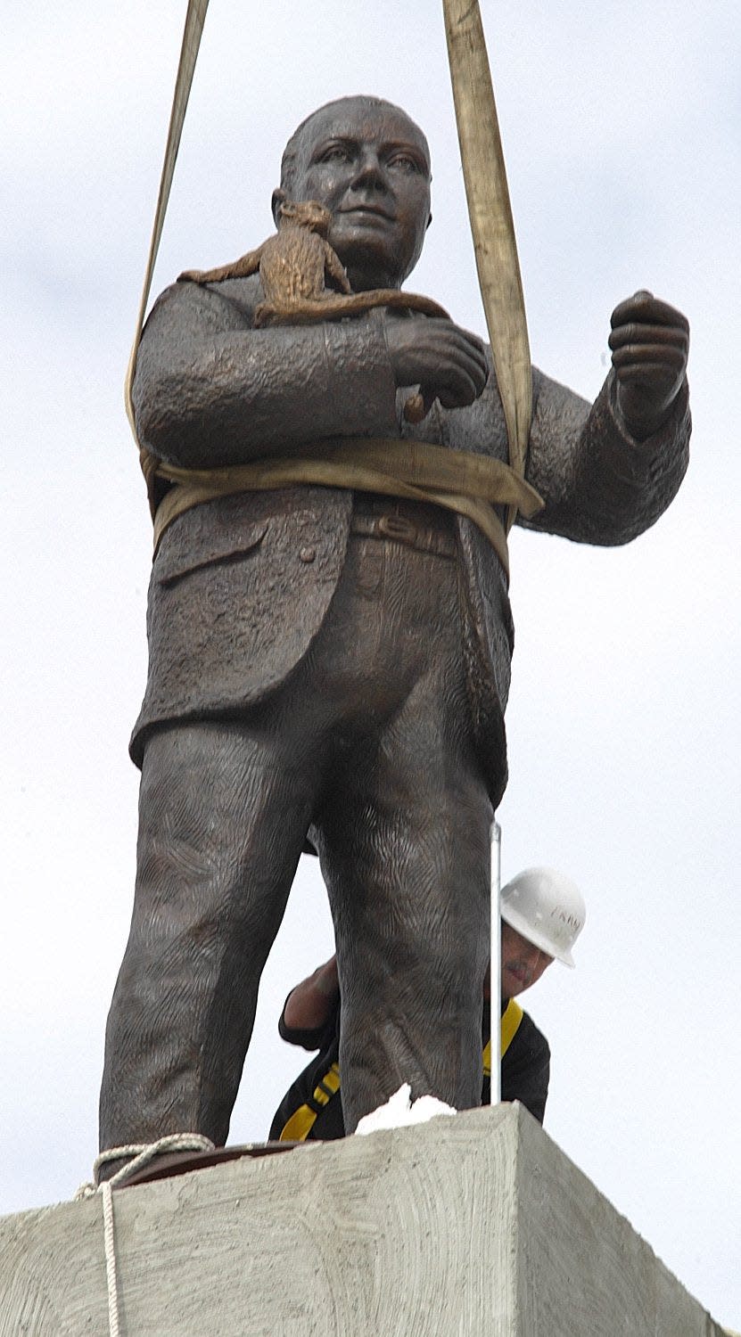 The scene in 2005 when the 3,000 pound, 11-foot-tall statue of Addison Mizner and his monkey were lifted to a perch above Royal Palm Place.