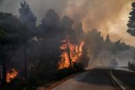 Flames rise next to a firefighting vehicle as a wildfire burns at the village of Kontodespoti, on the island of Evia