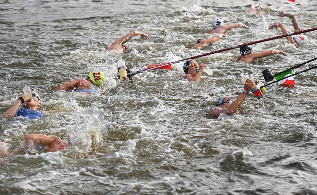 Competitors take refreshments at a feed station in the women's 10km marathon swimming event during the Tokyo 2020 Olympic Games at the Odaiba Marine Park in Tokyo on August 4, 2021. (AFP via Getty Images)