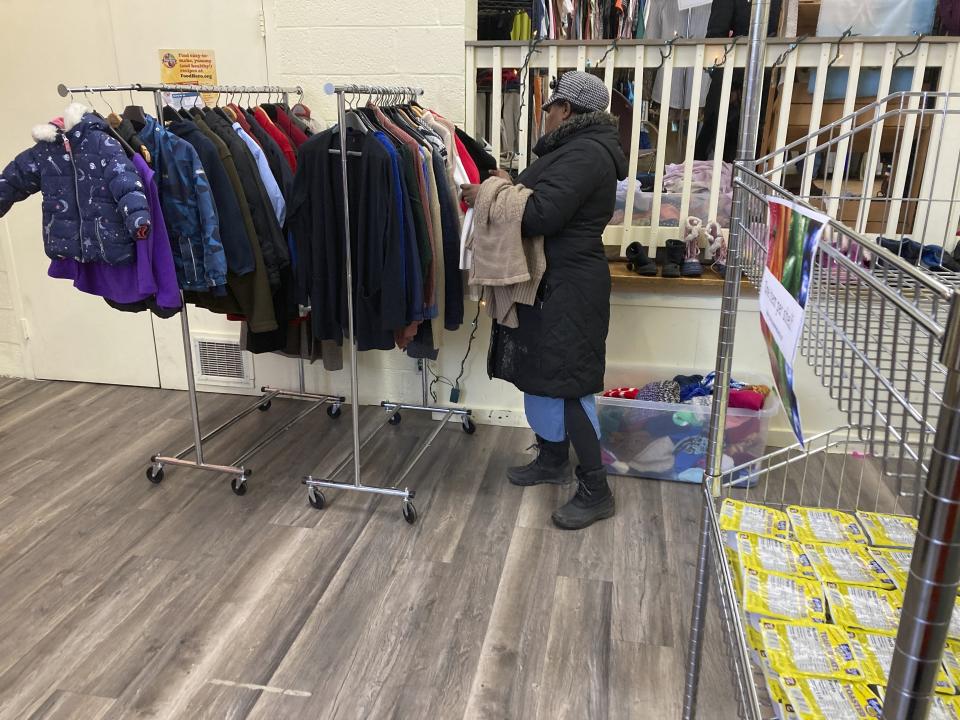 A Haitian immigrant looks through clothes at the Northeast Kingdom Community Action in St. Johnsbury, Vt. on Thursday March 23, 2023. The woman, her husband and three children, were dropped off in St. Johnsbury on Thursday by the U.S. Border Patrol. She asked that her photo only be taken from behind. The U.S. Border Patrol says agents are releasing some immigrants who were apprehended in Vermont after they entered the country illegally and dropping them off where they can catch public transportation. (AP Photo/Wilson Ring)