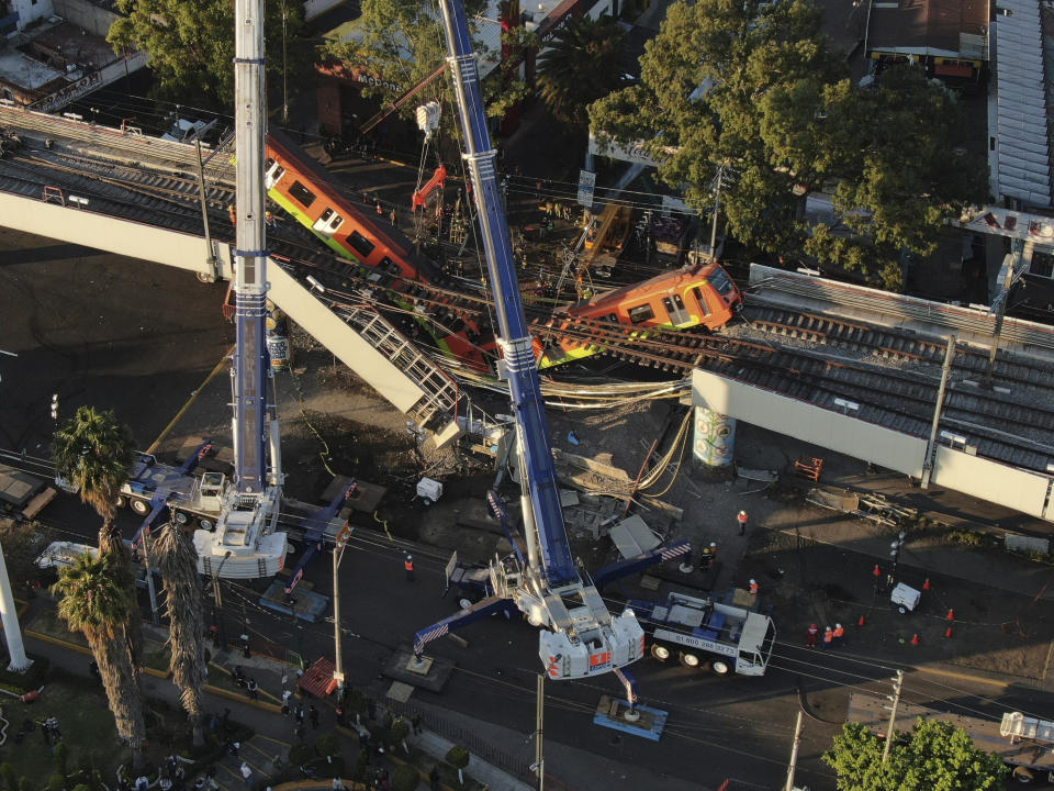 An aerial view of subway cars dangle at an angle from a collapsed elevated section of the metro, in Mexico City, Tuesday, May 4, 2021. The elevated section of Mexico City's metro collapsed late Monday killing at least 23 people and injuring at least 79, city officials said. (AP Photo/Fernando Llano)