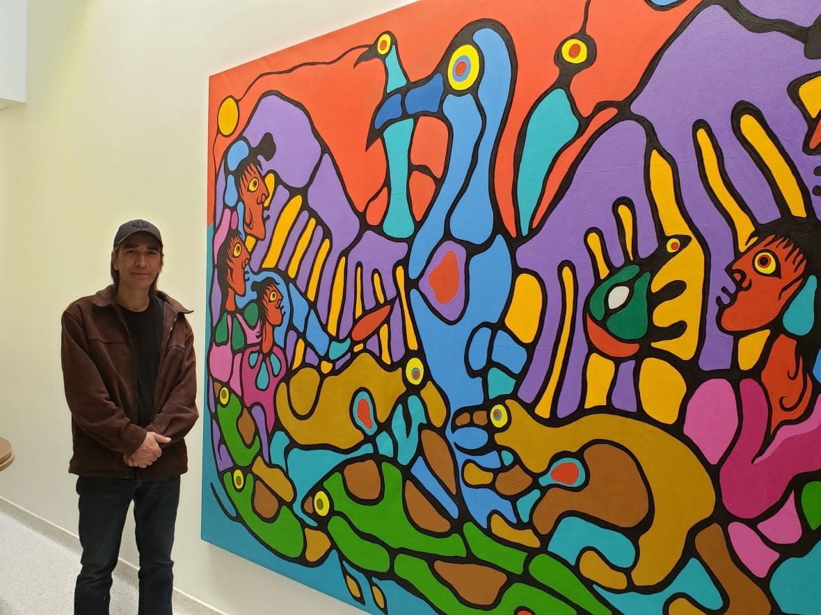 Benjamin Morrisseau, one of eight people charged in the Norval Morrisseau art forgery case, is shown in 2019 with one of his original works displayed at St. Joseph's Care Group's spiritual gathering lodge.  (St. Joseph's Care Group - image credit)