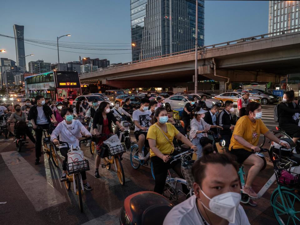 People wait to cross a busy street intersection during evening rush hour on May 30, 2022 in Beijing, China.