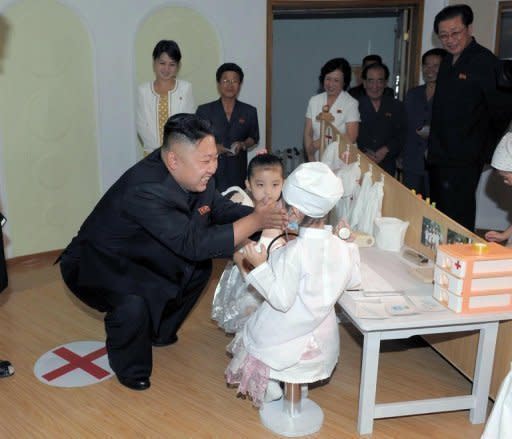 North Korean leader Kim Jong-Un talks to two children during a visit to the Kyongsang kindergarten in Pyongyang on July 15. Kim was accompanied by a woman believed to be Ri Sol-Ju (wearing yellow polka dot dress)