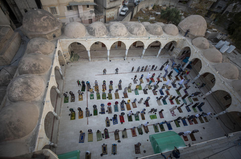 Musulmanes con mascarillas asisten a las plegarias del Eid al-Fitr ante una mezquita en Ciudad de Gaza, el domingo 24 de mayo de 2020. (AP Foto/Khalil Hamra)