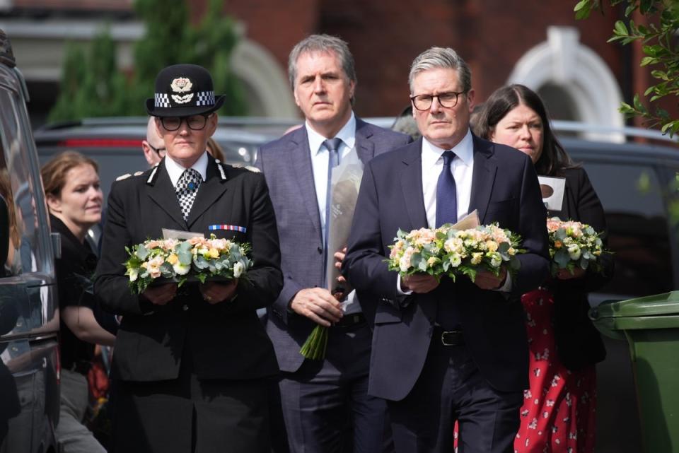 Keir Starmer arrives with a floral tribute to the child victims of Monday’s knife attack (Getty)