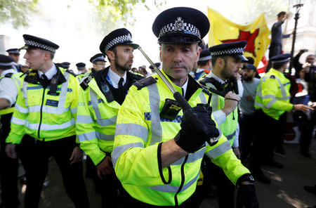 A police officer holds a baton during demonstrations outside Downing Street ahead of the visit by Turkey's President Recep Tayyip Erdogan, in London, Britain, May 15, 2018. REUTERS/Peter Nicholls