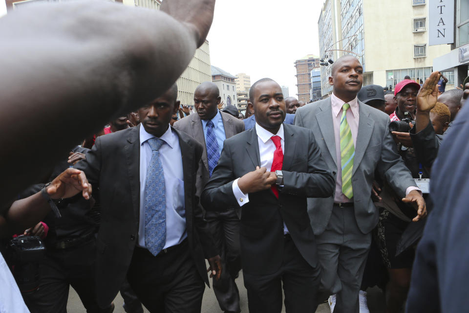 Zimbabwe top opposition leader Nelson Chamisa, center, arrives to deliver his speech at the party headquarters in Harare, Wednesday, Nov. 20, 2019. Zimbabwean police with riot gear fired tear gas and struck people who had gathered at the opposition party headquarters to hear a speech by the main opposition leader Nelson Chamisa who still disputes his narrow loss to Zimbabwean President Emmerson Mnangagwa. (AP Photo/Tsvangirayi Mukwazhi)