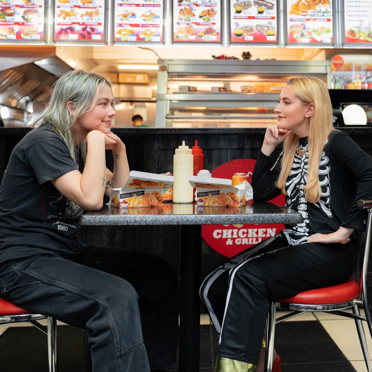 Singer Phoebe Bridgers (left) will be appearing on viral YouTube show Chicken Shop Date on Christmas Eve with host Amelia Dimoldenberg (right)  (Amelia Dimoldenberg )