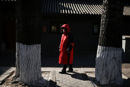 A public security volunteer poses for pictures as she keeps watch on a street ahead of the upcoming plenary session of National People's Congress (NPC), China's parliamentary body, in Beijing, China, March 1, 2018. REUTERS/Thomas Peter