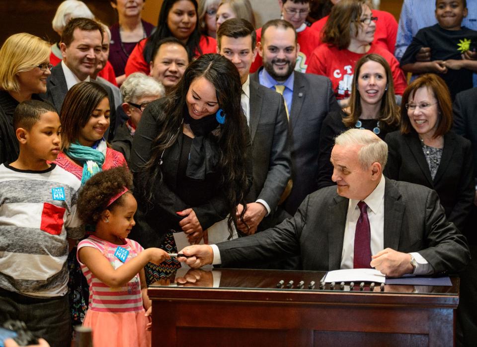 Governor Mark Dayton hands a pen to Ashia Rhodes after he signs a minimum wage bill into law at a public bill signing ceremony Monday, April 14, 2014 at the Minnesota State Capitol Rotunda in St. Paul. Minnesota goes from having one of the nation's lowest minimums to among the highest. With federal wage legislation stuck in Congress, states are rushing to fill the void. (AP Photo/The Star Tribune, Glen Stubbe) MANDATORY CREDIT; ST. PAUL PIONEER PRESS OUT; MAGS OUT; TWIN CITIES TV OUT