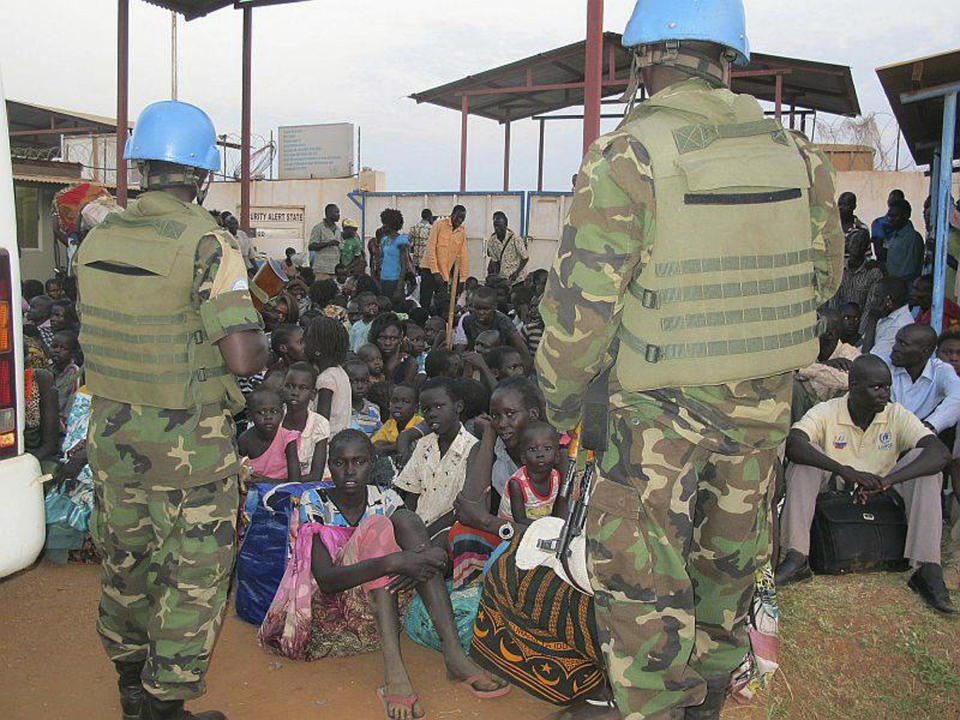 In this image released by the United Nations Mission Juba, United Nations soldiers stand guard as civilians gather at the compound of the United Nations Mission in the Republic of South Sudan (UNMISS), adjacent to Juba International Airport, to take refuge, Wednesday , Dec. 18 , 2013, in Juba, South Sudan. (AP Photo/UNMISS, Rolla Hinedi)
