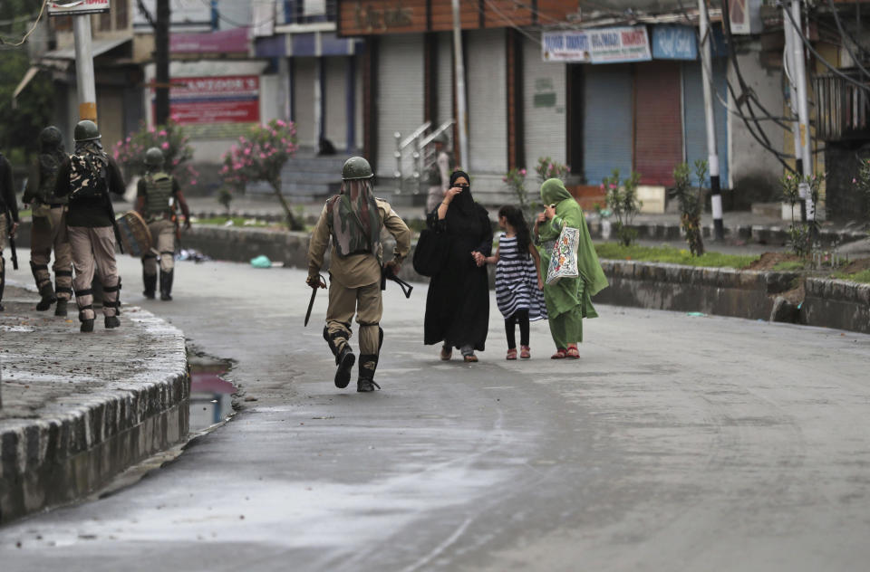 Kashmiris walks past Indian paramilitary soldiers patrolling a street in Srinagar, Indian controlled Kashmir, Saturday, Aug. 10, 2019. Authorities enforcing a strict curfew in Indian-administered Kashmir will bring in trucks of essential supplies for an Islamic festival next week, as the divided Himalayan region remained in a lockdown following India's decision to strip it of its constitutional autonomy. The indefinite 24-hour curfew was briefly eased on Friday for weekly Muslim prayers in some parts of Srinagar, the region's main city, but thousands of residents are still forced to stay indoors with shops and most health clinics closed. All communications and the internet remain cut off. (AP Photo/Mukhtar Khan)