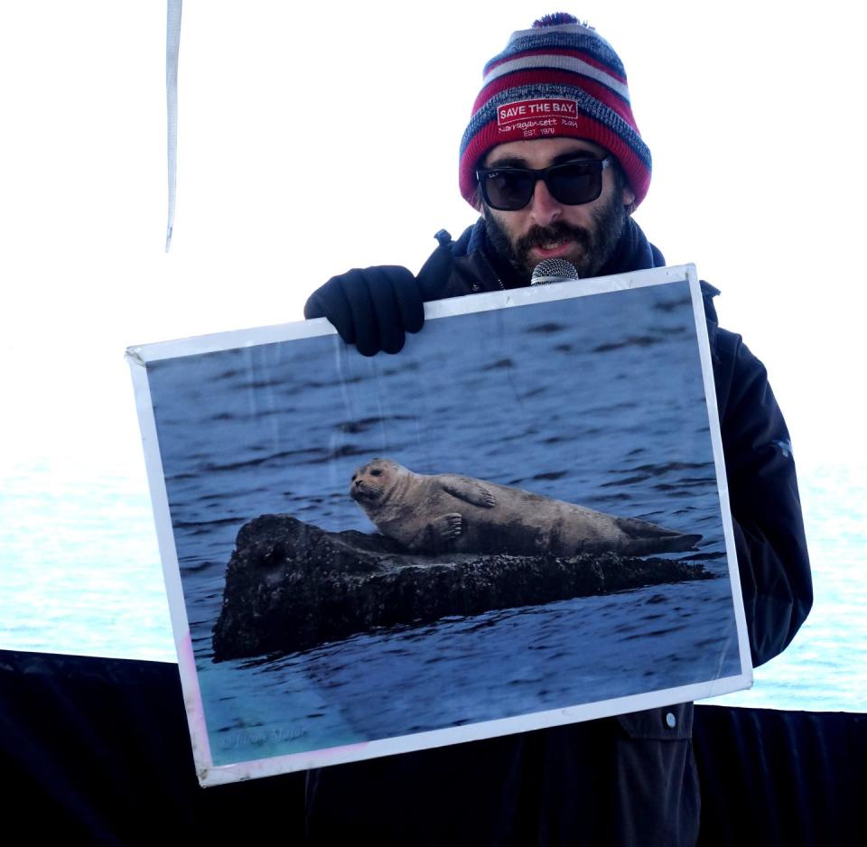 Save The Bay's Jeff Swanlund holds up a photo of a harbor seal while telling listeners on a tour about marine mammals. The seal tours are offered only in winter, when seals migrate here from Maine and coastal Canada.