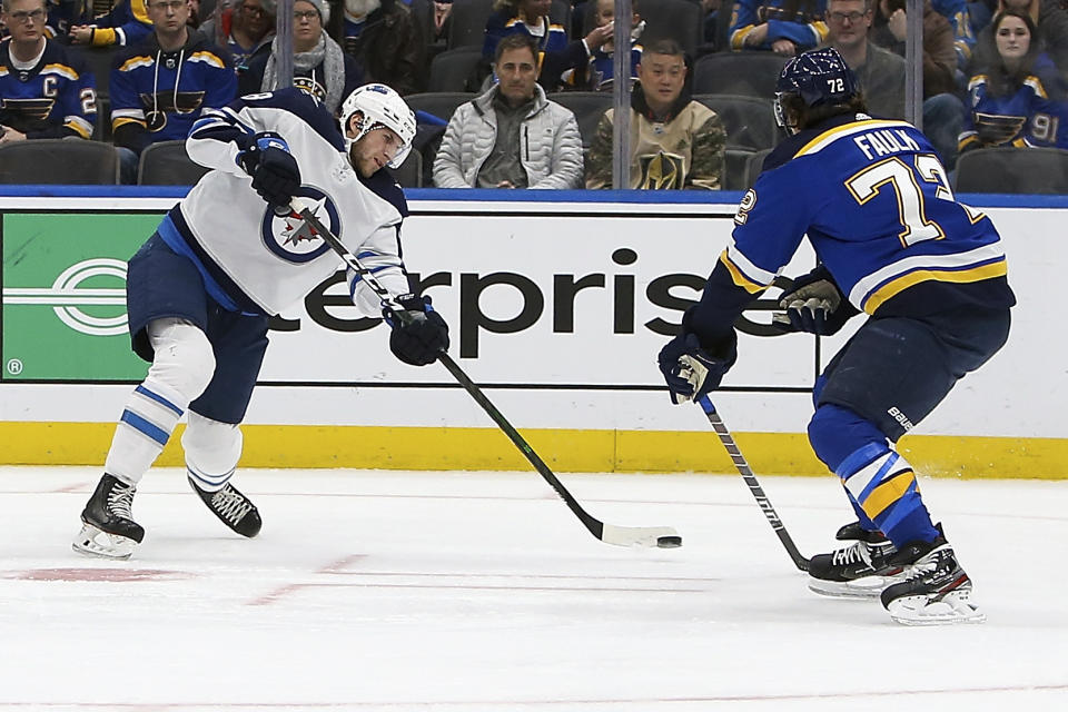 Winnipeg Jets' Jansen Harkins (58) shoots the puck to score as St. Louis Blues' Justin Faulk (72) defends during the first period of an NHL hockey game Thursday Feb. 6, 2020, in St. Louis. (AP Photo/Scott Kane)