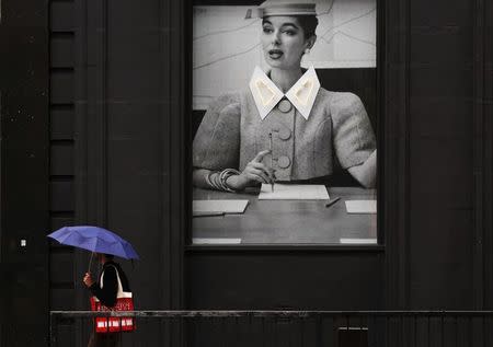 A man shelters under an umbrella as he passes a display at the Old Street roundabout dubbed "Silicon Roundabout" in London in this May 28, 2013 file photo. REUTERS/Luke Macgregor/Files