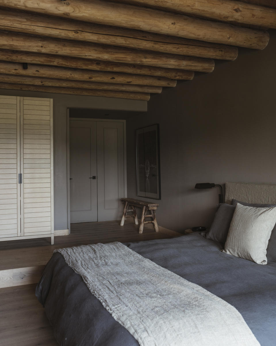 A bedroom with dark bedding and a light colored blanket