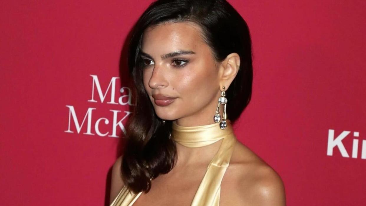 Emily Ratajkowski wears a yellow gown and  pair of dazzling earrings