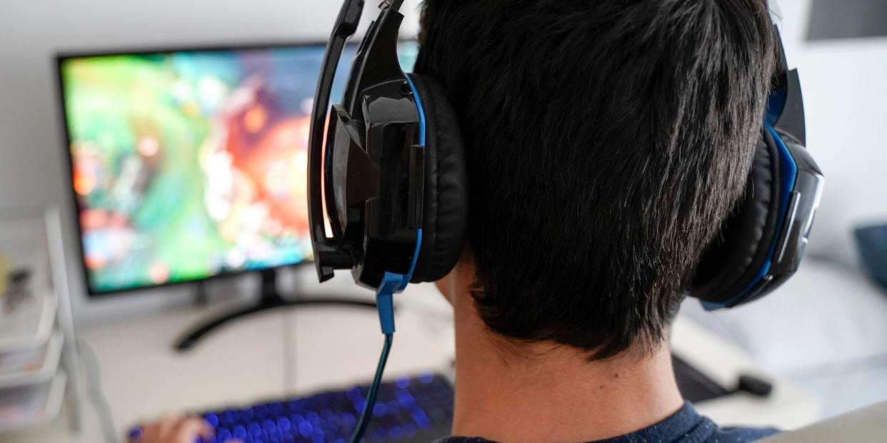 teen playing desktop computer game with headphones graphics