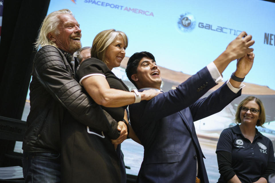 Virgin Galactic founder Sir Richard Branson picks up New Mexico Gov. Michelle Lujan Grisham while the company's Kevin Prieto takes a selfie during an event announcing Virgin Galactic's move to New Mexico Friday, May 10, 2019, at the state capital in Santa Fe, N.M. The company says is it nearing the first commercial flights from the Spaceport America. (AP Photo/Craig Fritz)