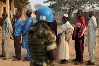 A United Nations security officer keeps guard as people wait in line to cast their votes during the second round of presidential and legislative elections in the mostly muslim PK5 neighbourhood of Bangui, Central African Republic, February 14, 2016. REUTERS/Siegfried Modola