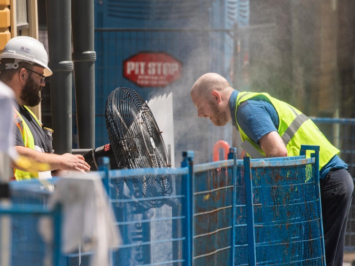 A construction worker uses a misting fan to cool down at a work site in Vancouver in June 2021.  (Ben Nelms/CBC - image credit)